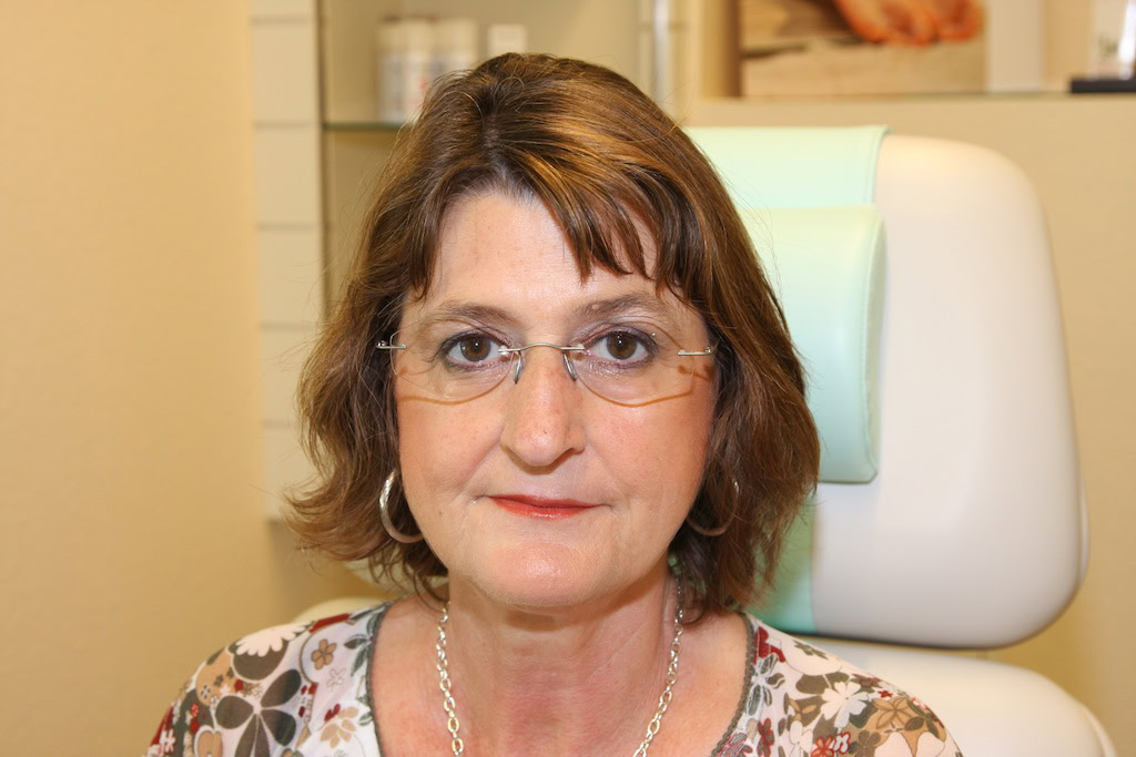 Frau mit Brille in einem Zimmer sitzend