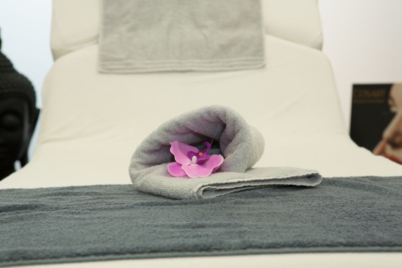 Graues Handtuch mit pinker Blume im Wellnessbereich