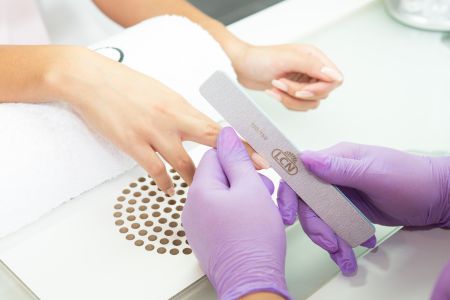 Maniküre: Hände mit Feile und Handschuhen