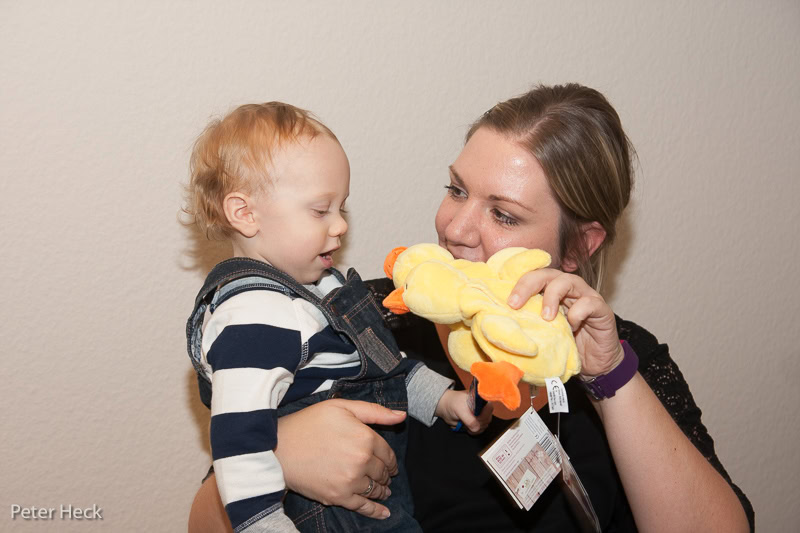 Frau hält Kind mit Plüschente im Arm.