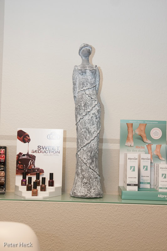 Statue neben Nagellacken und Fußpflegeprodukten