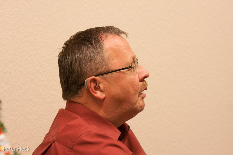 Mann mit Brille im Profil vor beiger Wand