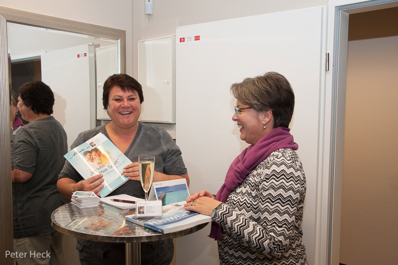 Zwei Frauen lachen bei einer Buchpräsentation.